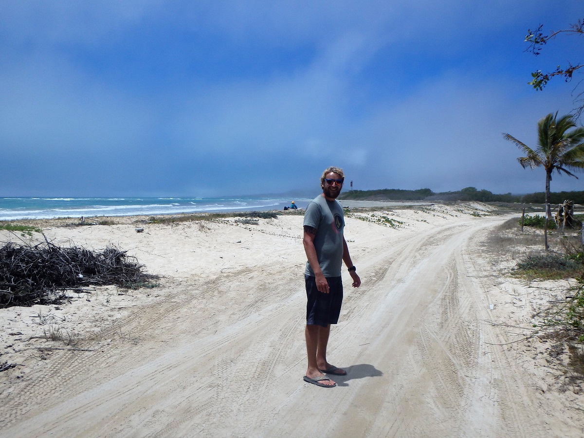 Rhys walking along a sandy road beside the shoreline