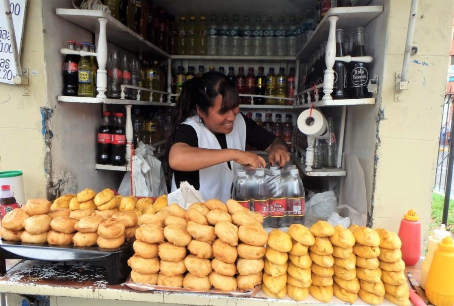 A local vendor selling smiling as she sells stacks of amazing street food