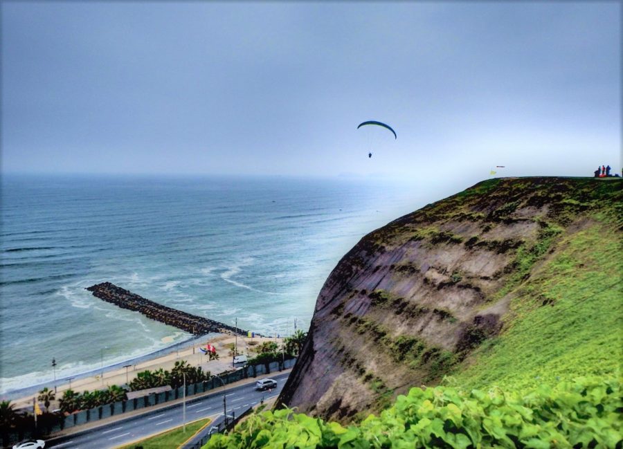 A paraglider soaring above the cliffs and the shore