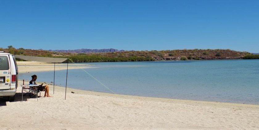 Rhys relaxing outside our campervan on a beach in Baja Mexico